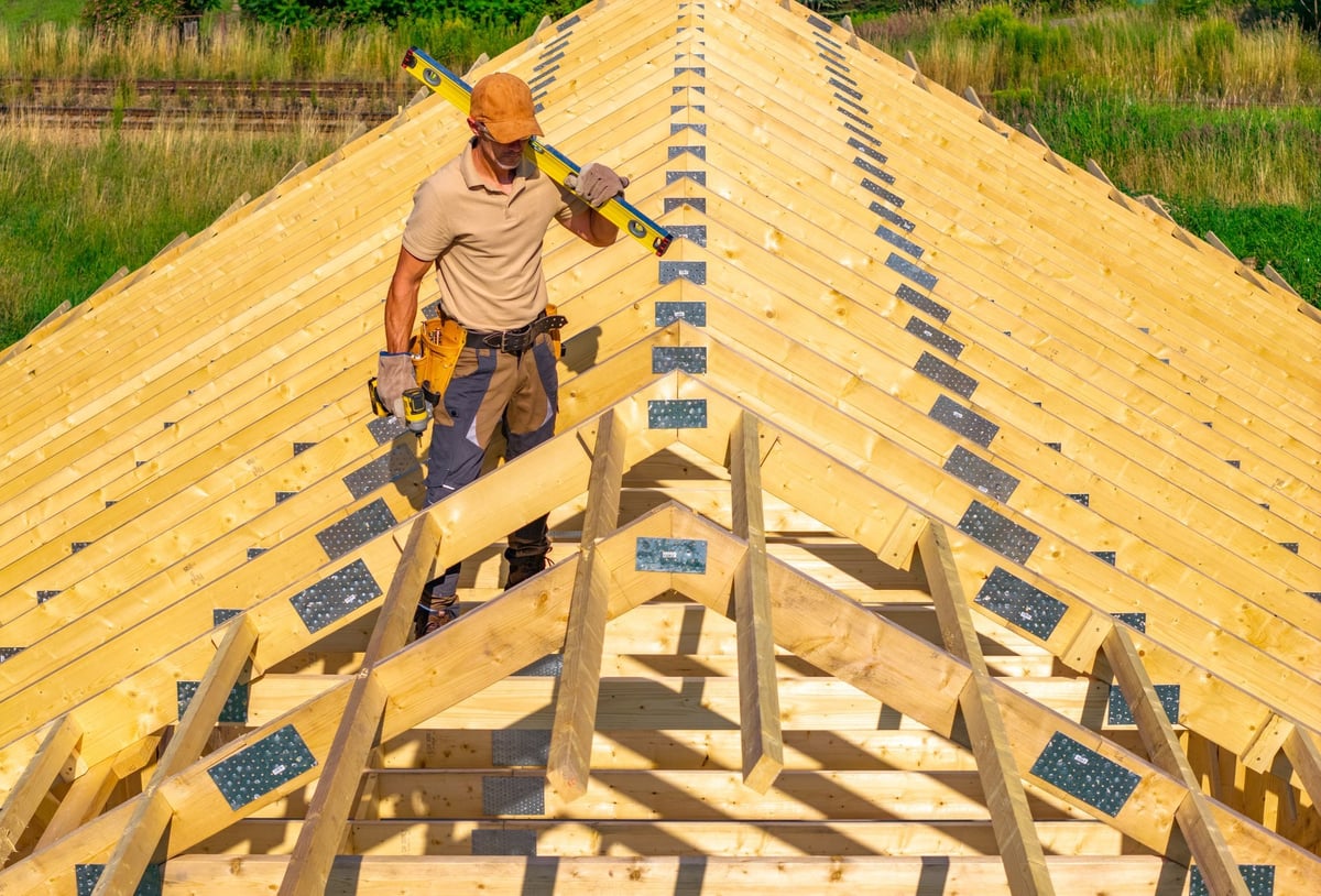 Construction worker aligning wooden roof framework during installation