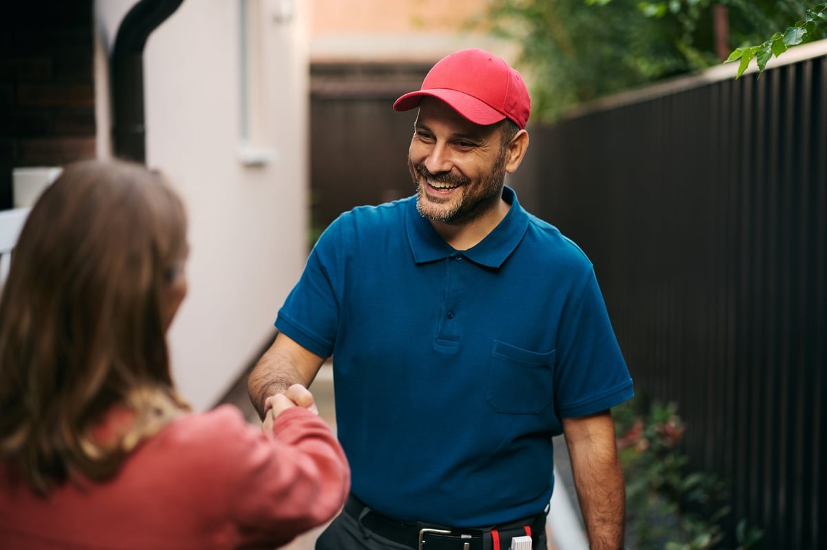 Happy handyman handshaking with customer